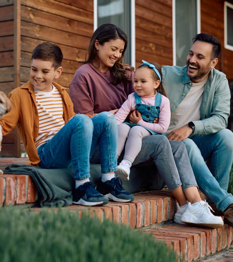 Happy family relaxing with their dog on staircase in the backyard.